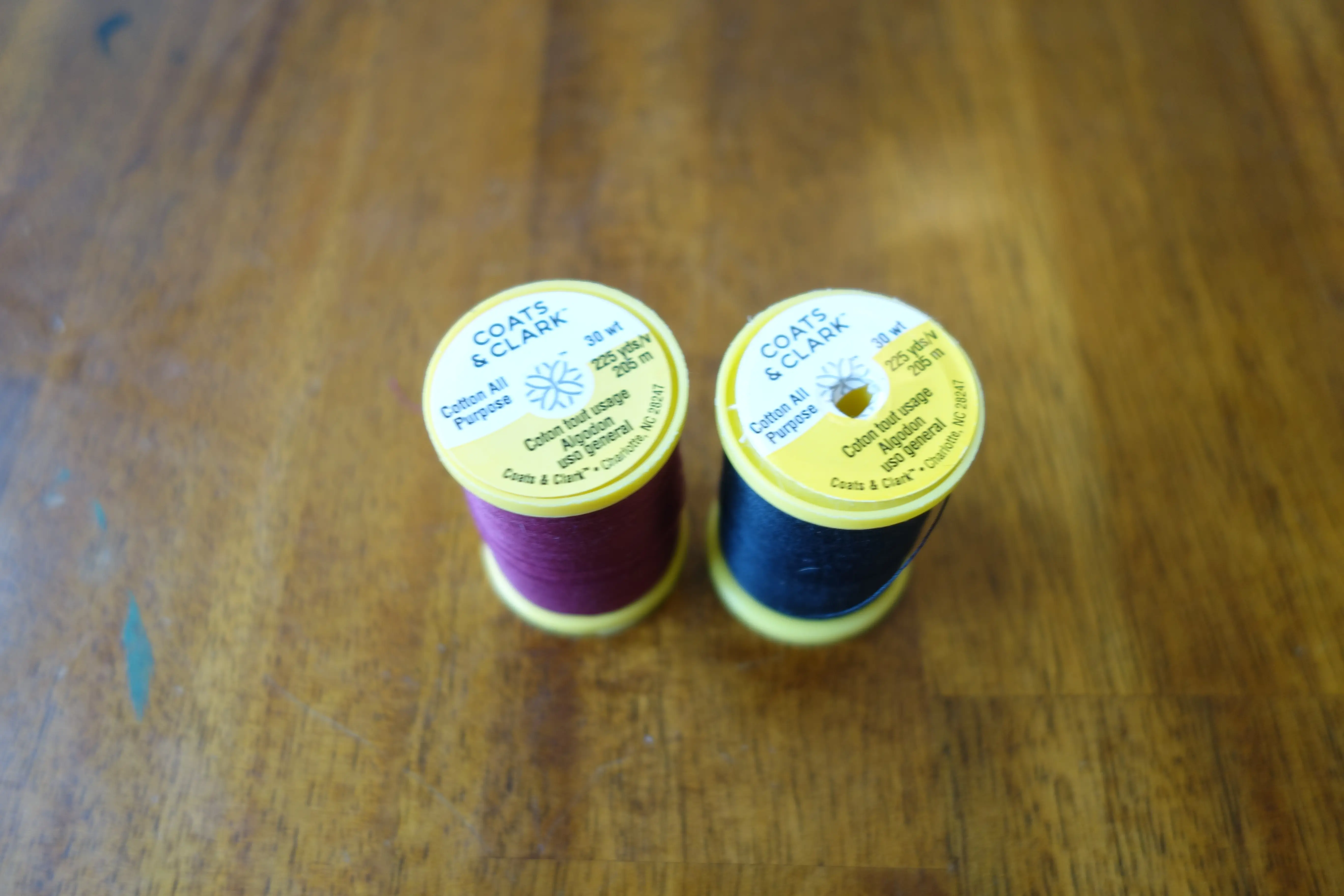 two spools of cotton sewing thread, one red, one black