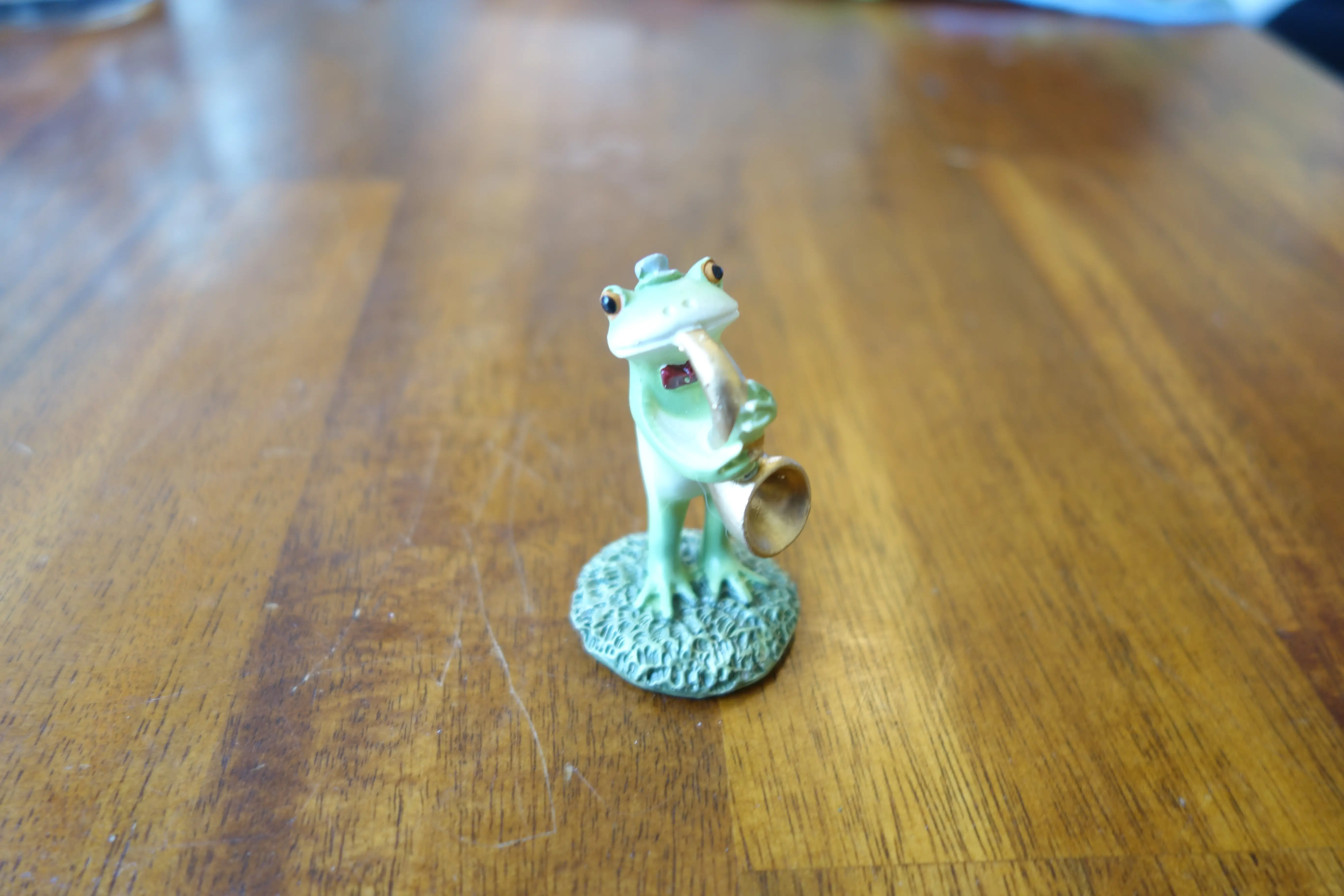 a small frog figure playing saxaphone and wearing a little hat and bowtie