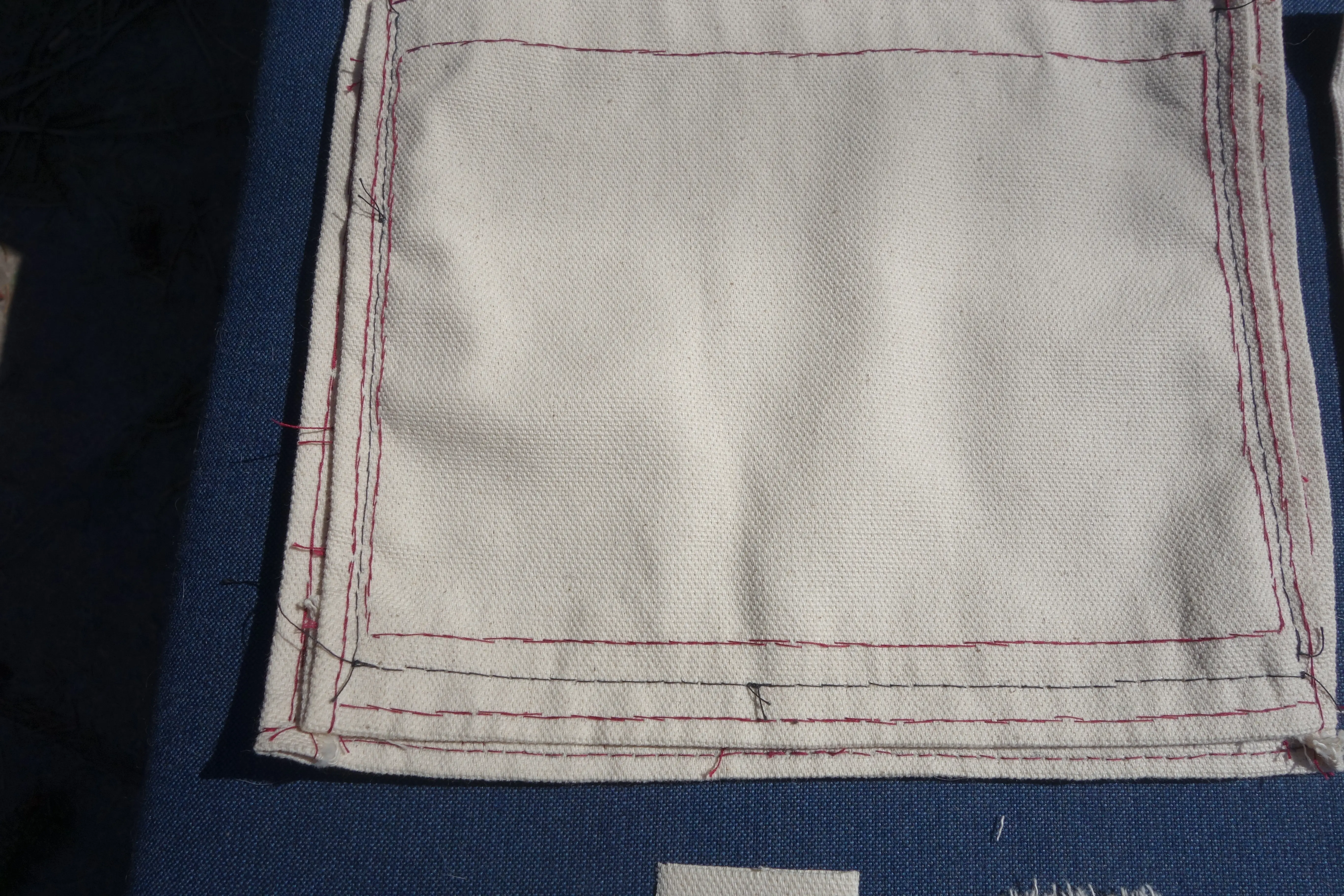 two canvas panels attached together with black thread